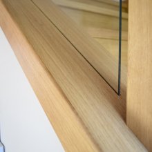 Dubový obklad betónového schodiska so zábradlím drevo/sklo s dizajnovými prechodmi madiel.